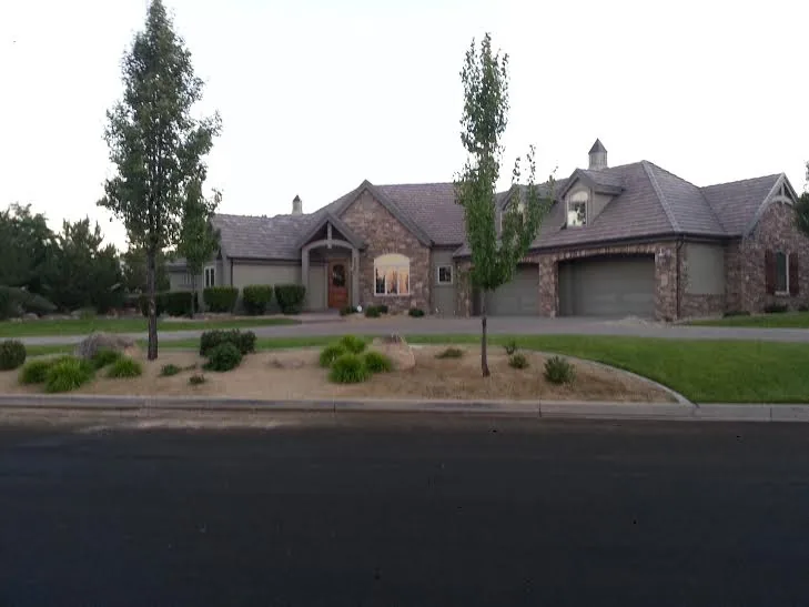 Stone-and-stucco Reno home with fresh sod, mature trees and tidy planting beds along the street